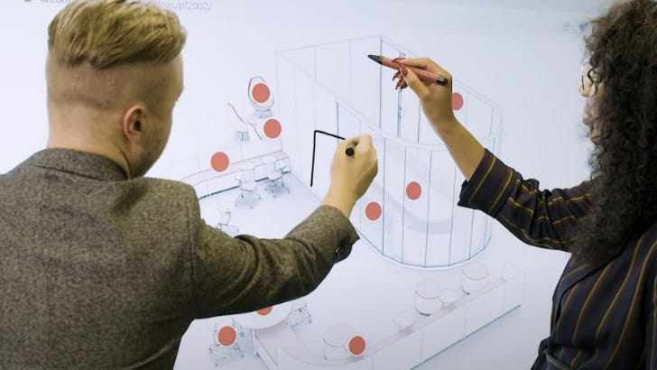 Collaborative design session on a SMART interactive display in a manufacturing design studio.
