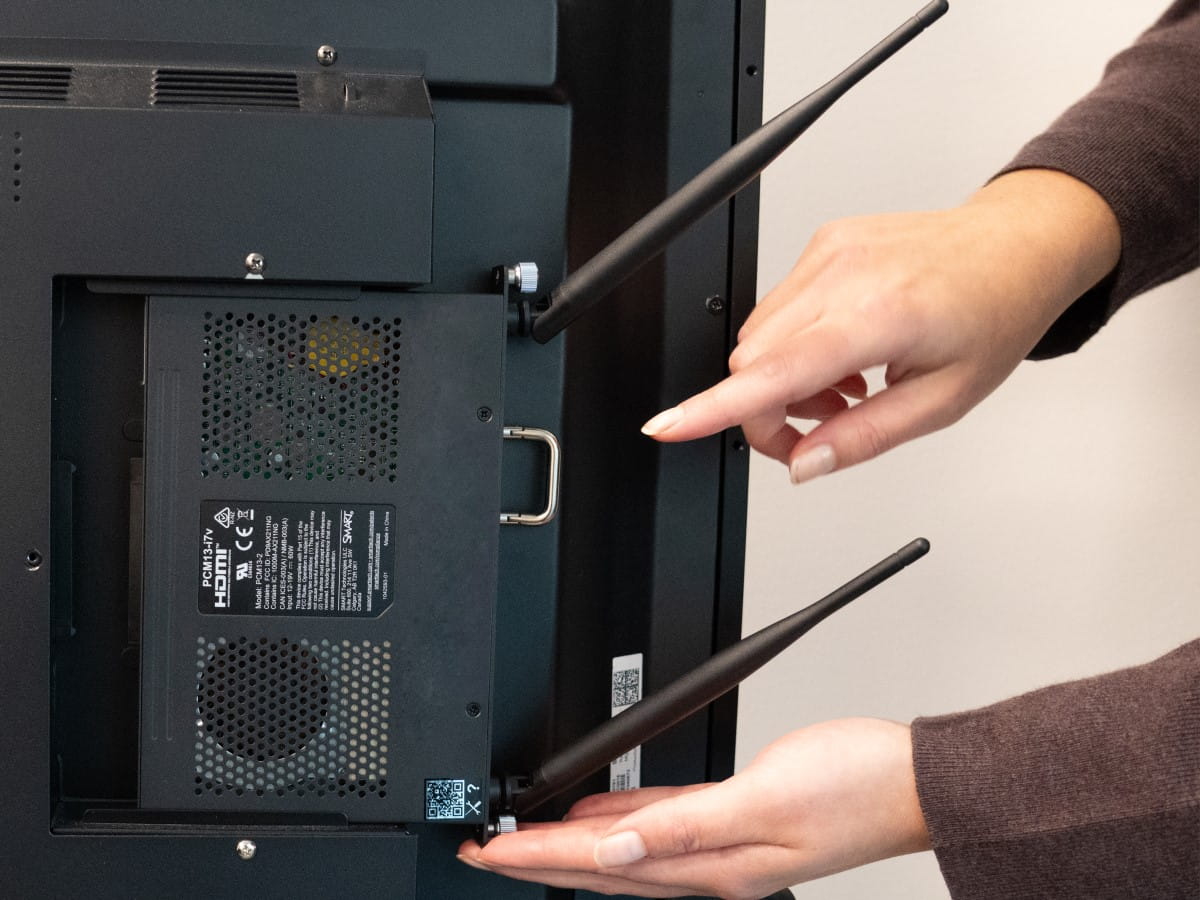 Hands demonstrating the installation of an OPS PC module into a SMART Board interactive display.